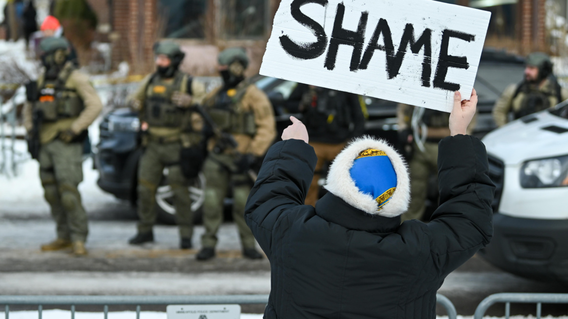 Жена издига плакат с надпис "Срам" на мястото на инцидента в Минеаполис